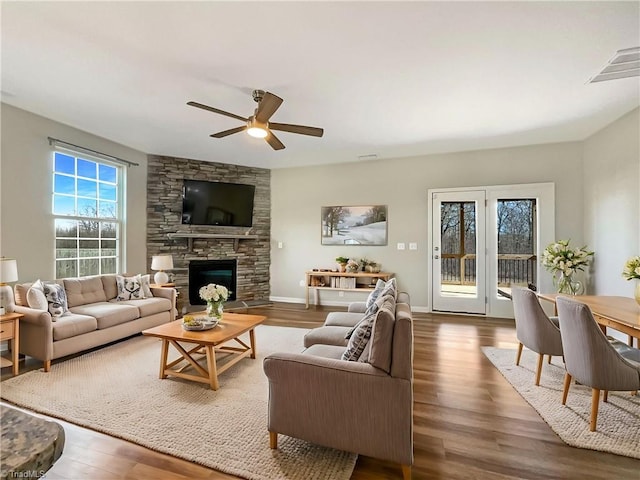 living room with baseboards, visible vents, ceiling fan, wood finished floors, and a fireplace