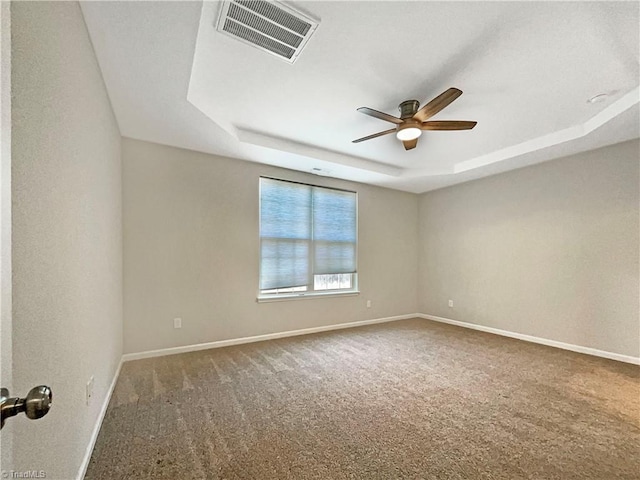 carpeted empty room with a raised ceiling, visible vents, and baseboards