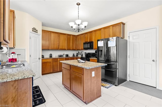 kitchen featuring stainless steel appliances, light stone countertops, hanging light fixtures, a chandelier, and a kitchen island