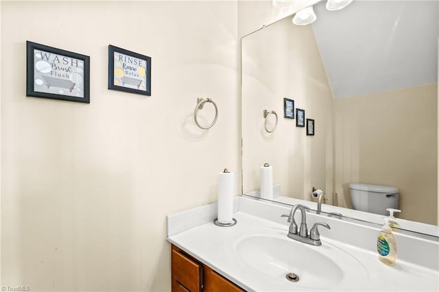 bathroom featuring vanity, toilet, and vaulted ceiling