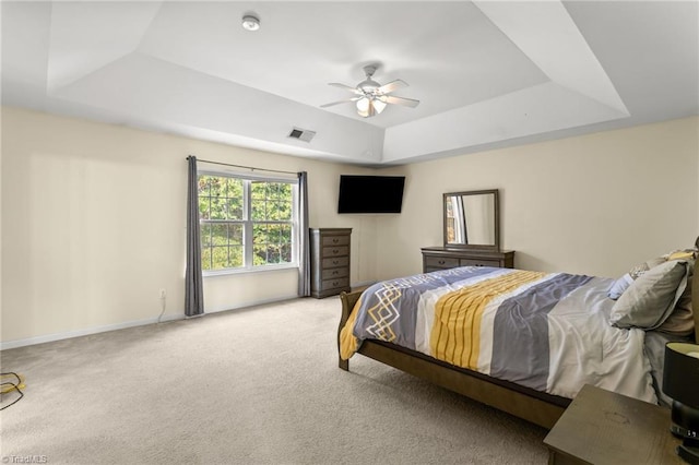 bedroom featuring ceiling fan, light carpet, and a tray ceiling