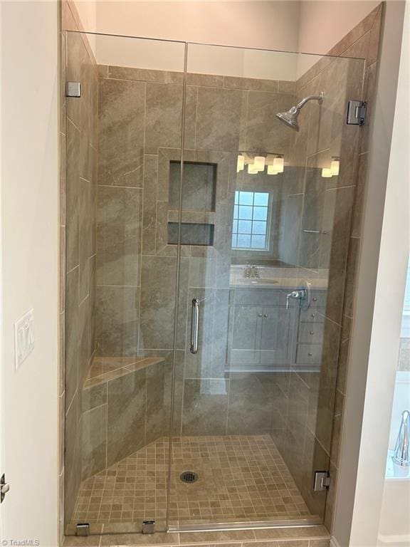 bathroom with a shower with door and sink