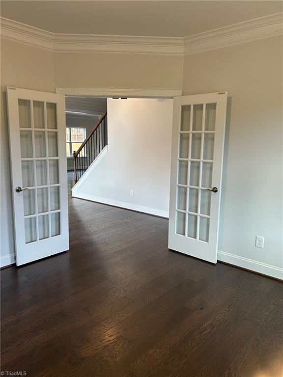 empty room with dark wood-type flooring and french doors