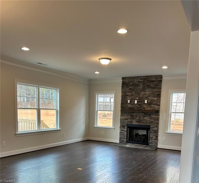 unfurnished living room featuring crown molding, a healthy amount of sunlight, a stone fireplace, and dark wood-type flooring