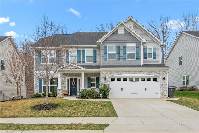 craftsman house with a front yard, concrete driveway, stone siding, and an attached garage