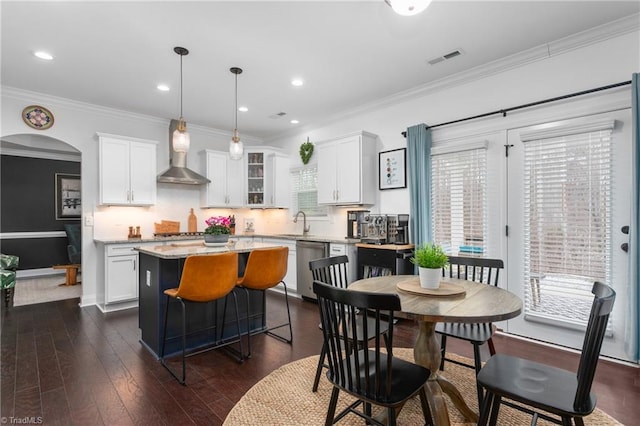 dining room featuring dark wood finished floors, visible vents, arched walkways, and ornamental molding