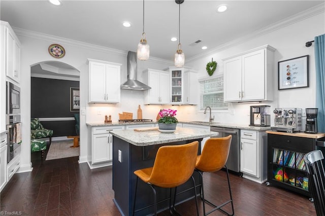 kitchen with white cabinets, wall chimney exhaust hood, arched walkways, and appliances with stainless steel finishes