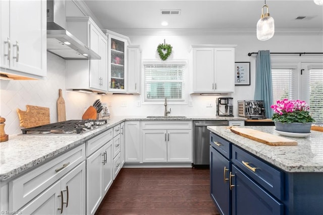 kitchen featuring a sink, white cabinets, appliances with stainless steel finishes, wall chimney range hood, and blue cabinets