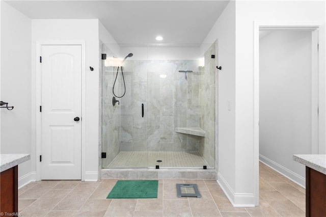 bathroom with baseboards, a stall shower, vanity, and tile patterned flooring