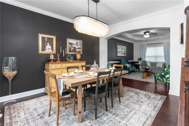 dining room featuring ceiling fan, baseboards, ornamental molding, wood finished floors, and arched walkways