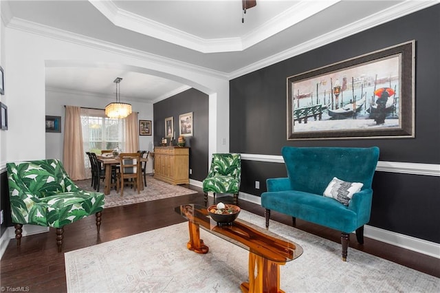 living area with baseboards, arched walkways, wood finished floors, and crown molding