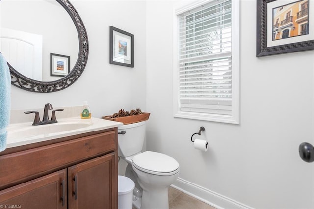 half bath featuring tile patterned floors, toilet, vanity, and baseboards