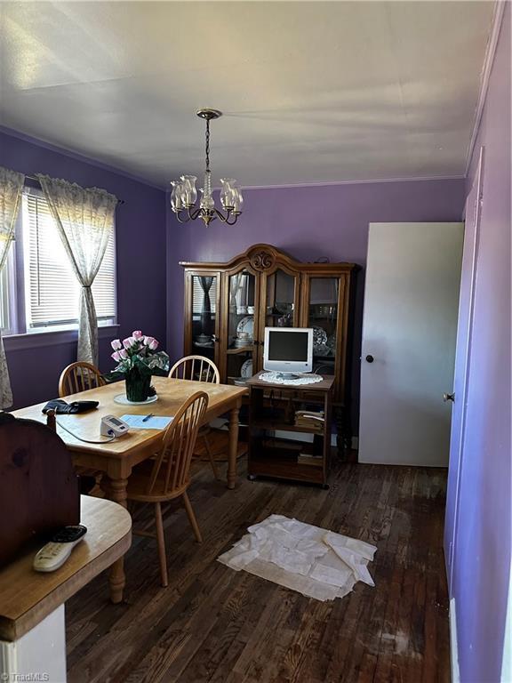 dining area with dark wood finished floors and an inviting chandelier