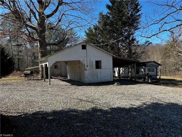 view of outdoor structure with an attached carport and driveway