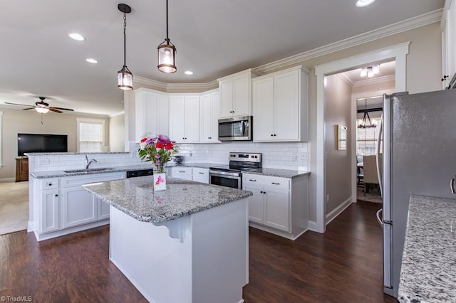 kitchen with stainless steel appliances, a kitchen island, a sink, and white cabinets