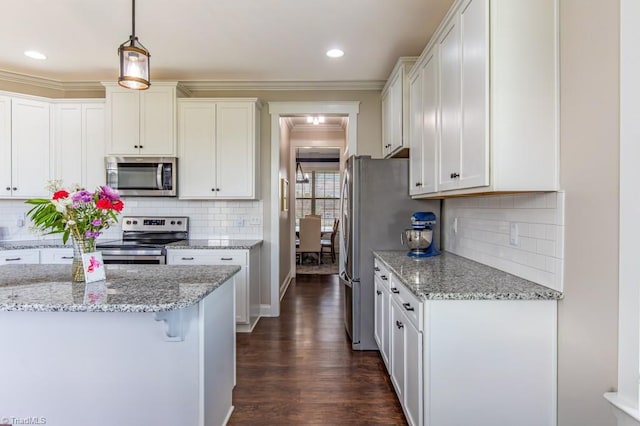 kitchen with appliances with stainless steel finishes, dark wood-style flooring, decorative light fixtures, crown molding, and white cabinetry