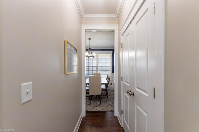 corridor featuring an inviting chandelier, baseboards, ornamental molding, and dark wood-style flooring