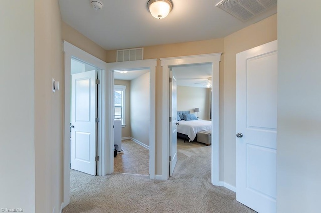 corridor featuring carpet floors, baseboards, and visible vents