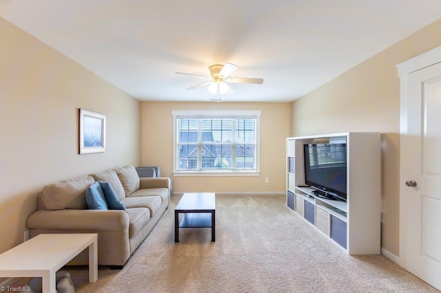 living area with baseboards, a ceiling fan, and light colored carpet