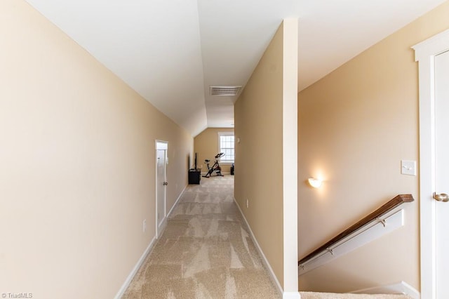 hall featuring light carpet, visible vents, an upstairs landing, vaulted ceiling, and baseboards