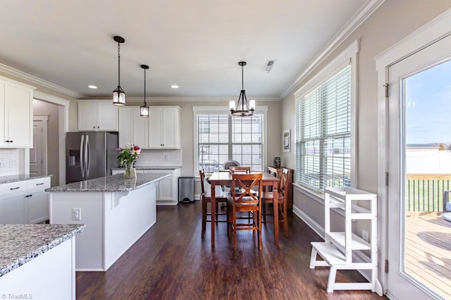 kitchen featuring a center island, dark wood-style flooring, stainless steel refrigerator with ice dispenser, ornamental molding, and white cabinetry