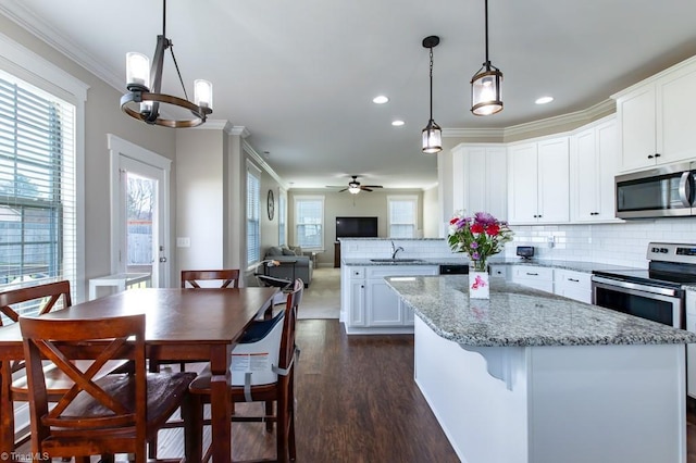 kitchen with backsplash, appliances with stainless steel finishes, ornamental molding, a healthy amount of sunlight, and a sink