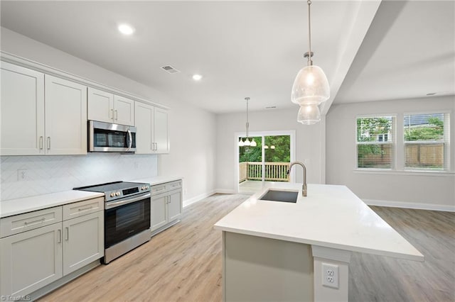 5421 High Valley Ln, Winston-Salem, NC 27104 - kitchen featuring stainless steel appliances, backsplash, light wood-style flooring, a center island with sink, and recessed lighting
