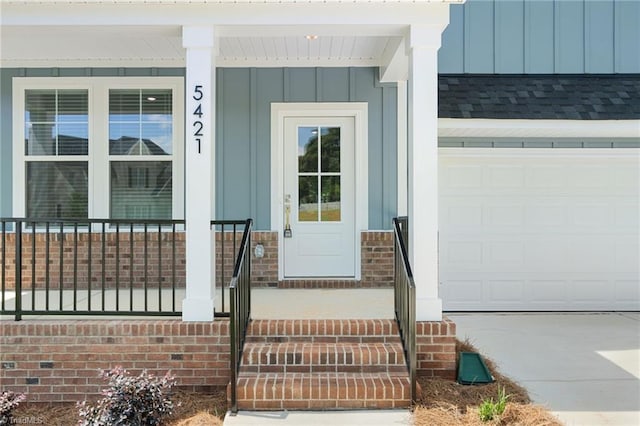 5421 High Valley Ln, Winston-Salem, NC 27104 - view of exterior entry with board and batten siding, a garage, covered porch, driveway, and roof with shingles