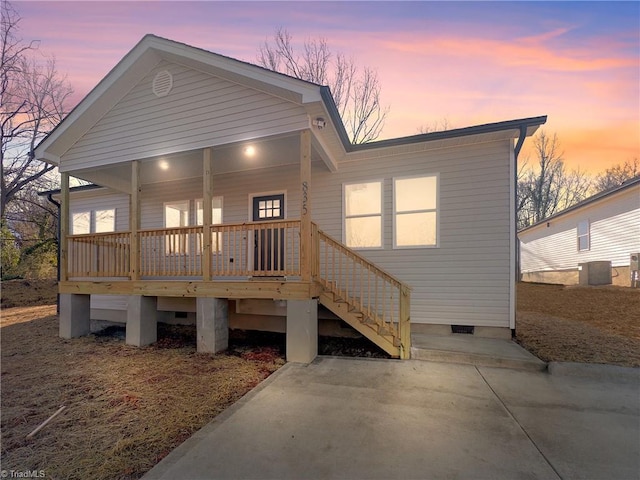 back house at dusk with central AC unit and covered porch