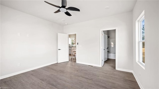 unfurnished bedroom with multiple windows, dark hardwood / wood-style flooring, connected bathroom, and ceiling fan