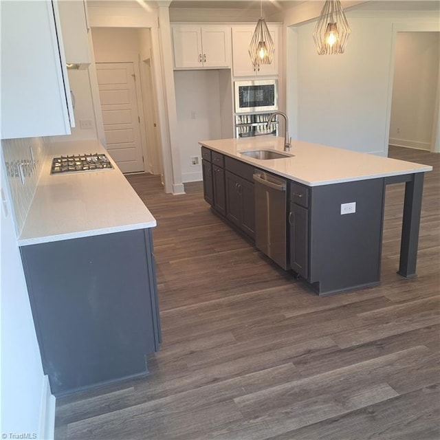 kitchen featuring dark wood-style flooring, a sink, light countertops, appliances with stainless steel finishes, and white cabinetry