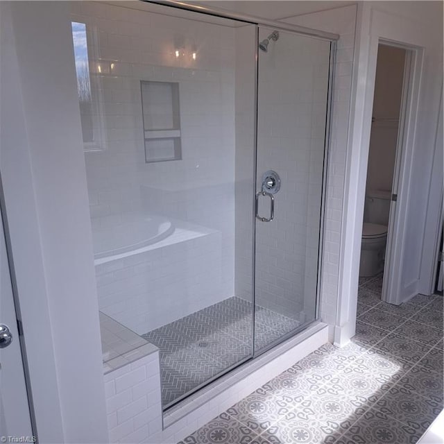 bathroom with tile patterned flooring, toilet, tiled tub, and a stall shower