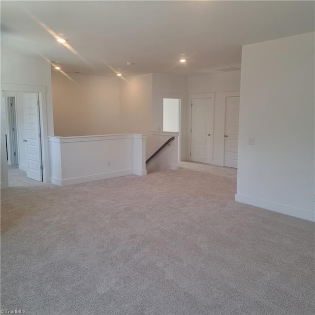 spare room with recessed lighting, baseboards, and light carpet