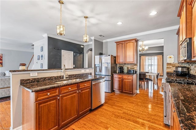 kitchen with sink, crown molding, appliances with stainless steel finishes, pendant lighting, and backsplash