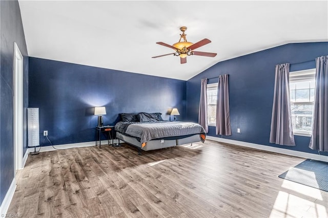 bedroom with multiple windows, ceiling fan, lofted ceiling, and light hardwood / wood-style flooring