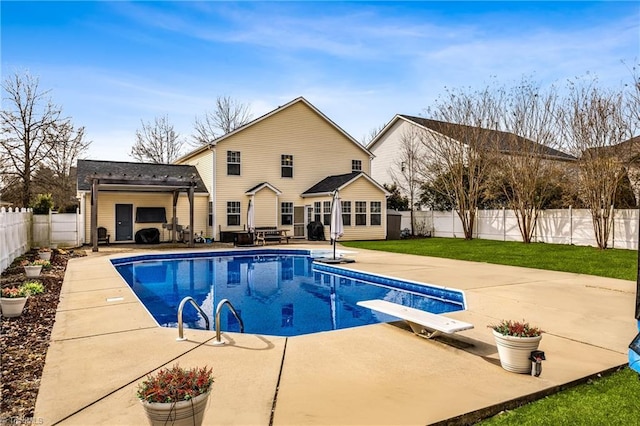 view of swimming pool featuring an outbuilding, a diving board, a patio, and a lawn