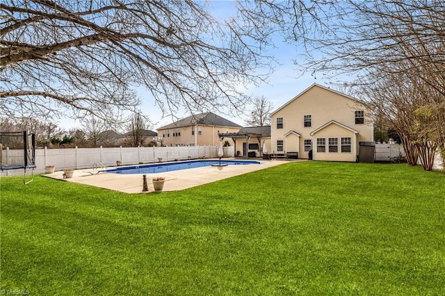 exterior space with a trampoline, a fenced in pool, a yard, and a patio area