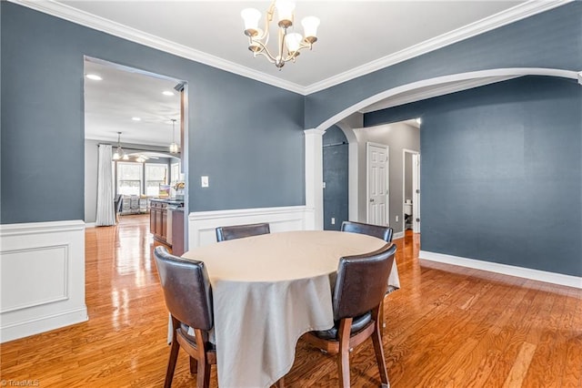 dining space featuring ornamental molding, a notable chandelier, and light wood-type flooring