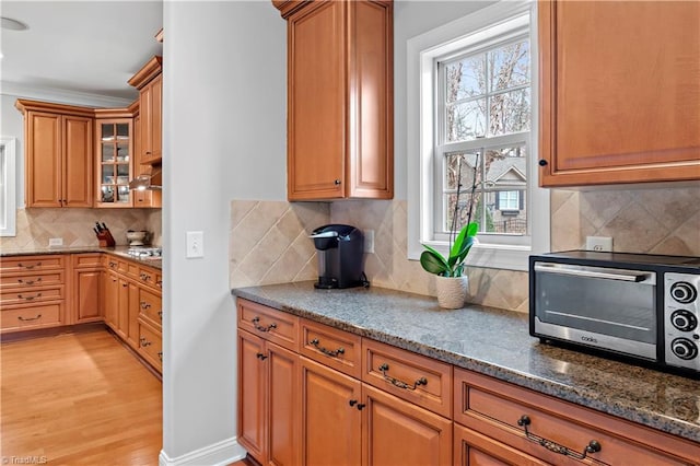 kitchen featuring tasteful backsplash, dark stone counters, and light wood-type flooring