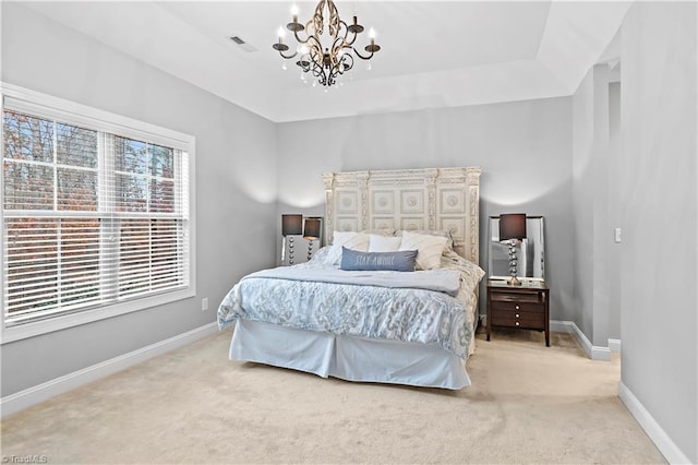 carpeted bedroom featuring a tray ceiling and a chandelier