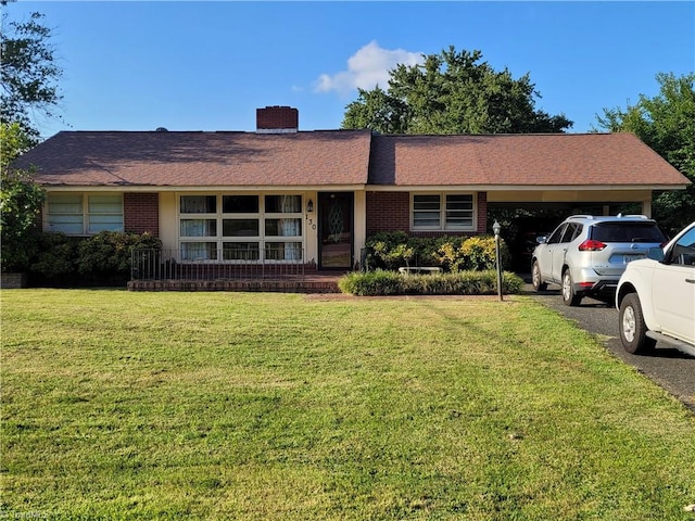 ranch-style home featuring a carport and a front lawn