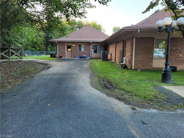 view of property exterior with central AC unit and a lawn