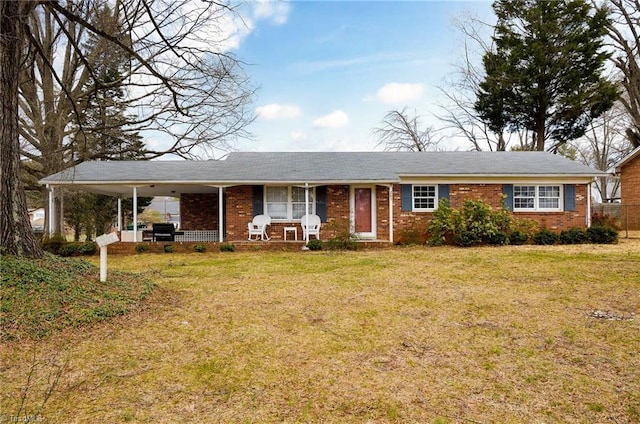 ranch-style house with a porch, a front yard, brick siding, and an attached carport