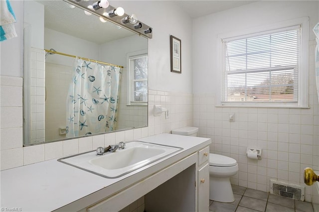 full bath with visible vents, toilet, tile patterned floors, vanity, and tile walls