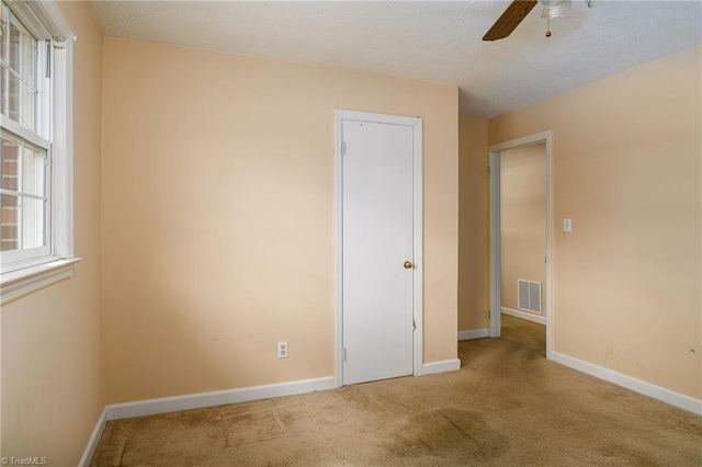 unfurnished bedroom with visible vents, baseboards, ceiling fan, carpet, and a textured ceiling