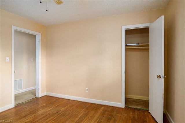 unfurnished bedroom featuring a closet, visible vents, baseboards, and wood finished floors