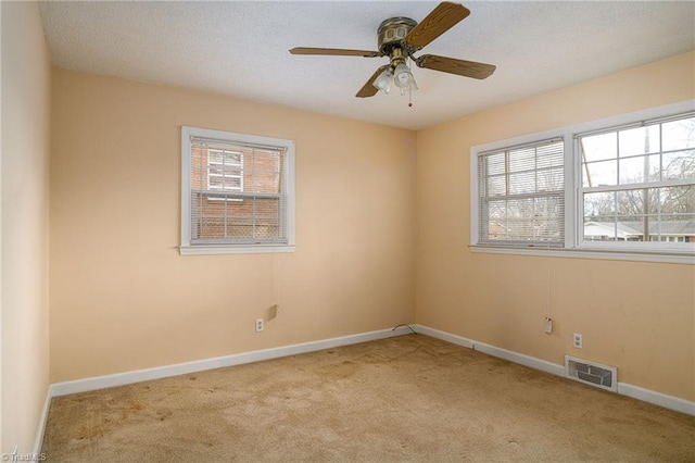 carpeted empty room featuring baseboards, visible vents, and a ceiling fan