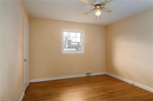 spare room with visible vents, a ceiling fan, a textured ceiling, wood finished floors, and baseboards