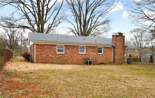 rear view of house with central air condition unit, brick siding, fence, a yard, and a chimney