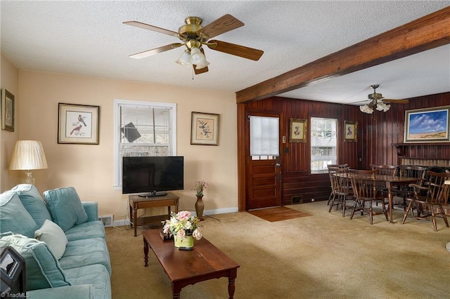 living room featuring carpet floors, wood walls, a textured ceiling, and beamed ceiling